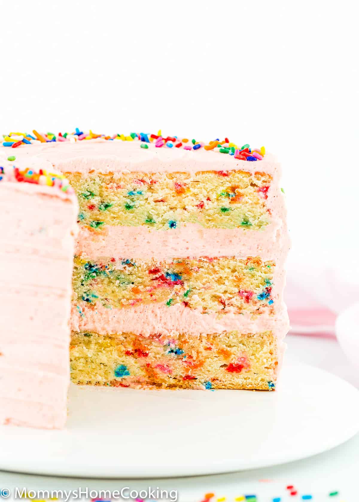 cut eggless funfetti cake on a white serving plate.