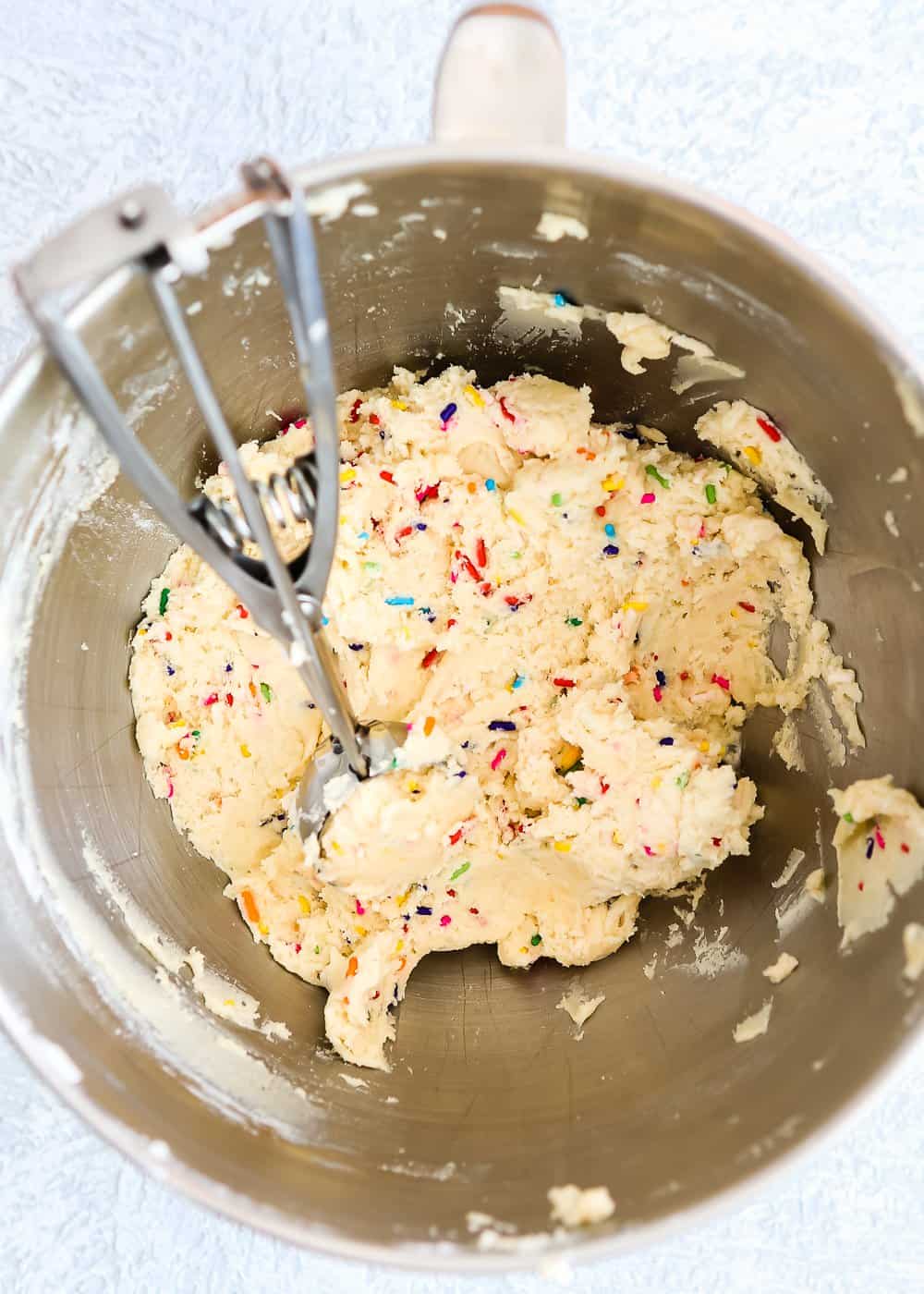 egg-free cookie dough in a bowl of a stand mixer with a ice cream scoop. 