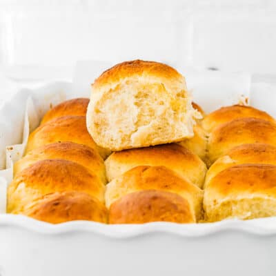 a egg-free homemade hawaiian roll over a baking pan with more rolls.