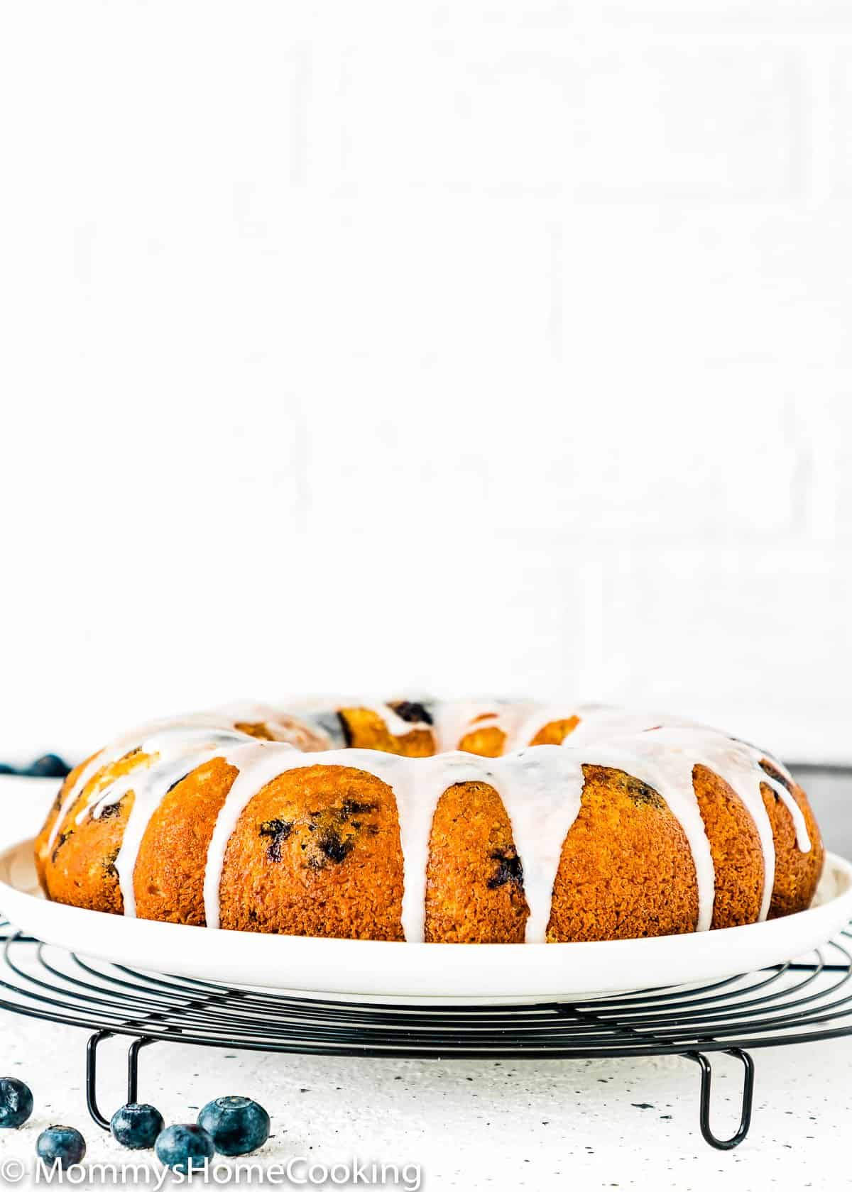 Eggless Lemon Blueberry Cake with glaze on a white serving plate