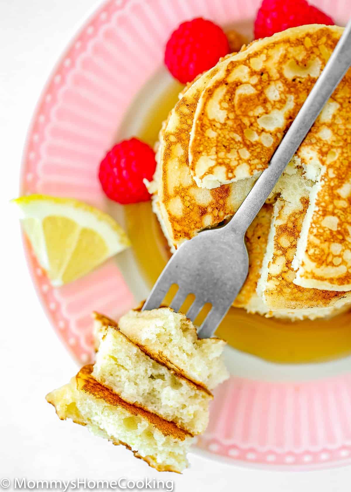 a fork with eggless lemon pancakes showing fluffy inside texture. 