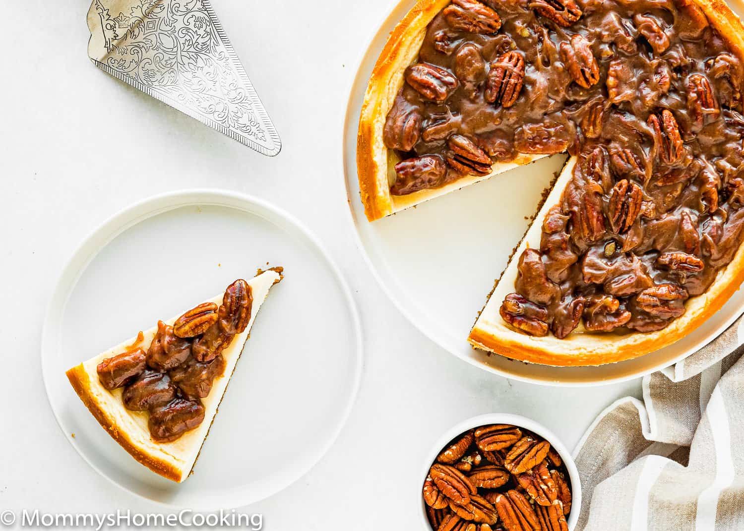 slice of egg-free pecan pie cheesecake on a plate with pecan in a bowl on the side.