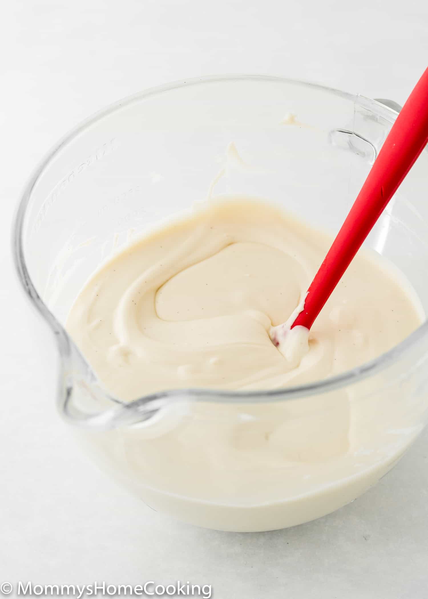 Eggless Cheesecake batter in a mixing bowl with a spatula.