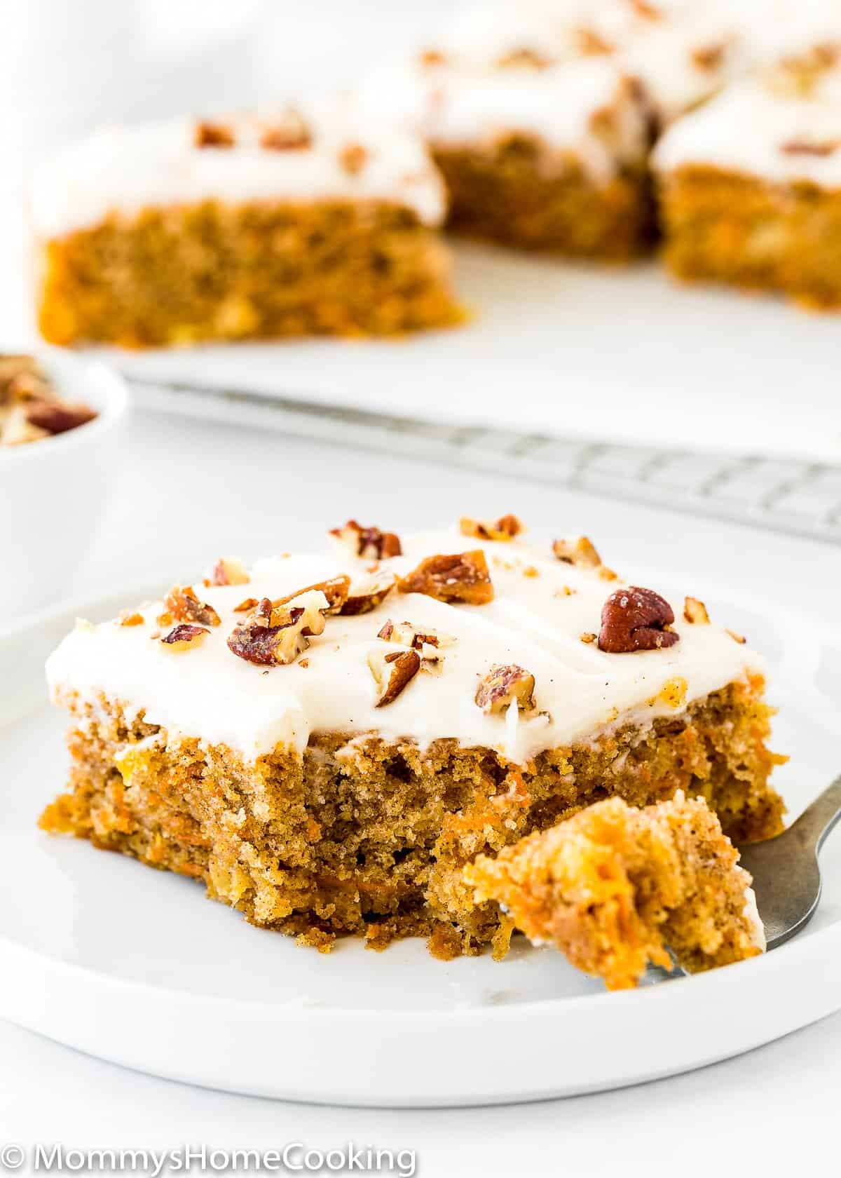 slices of Eggless Pineapple Carrot Sheet Cake with a spoon on a white plate.