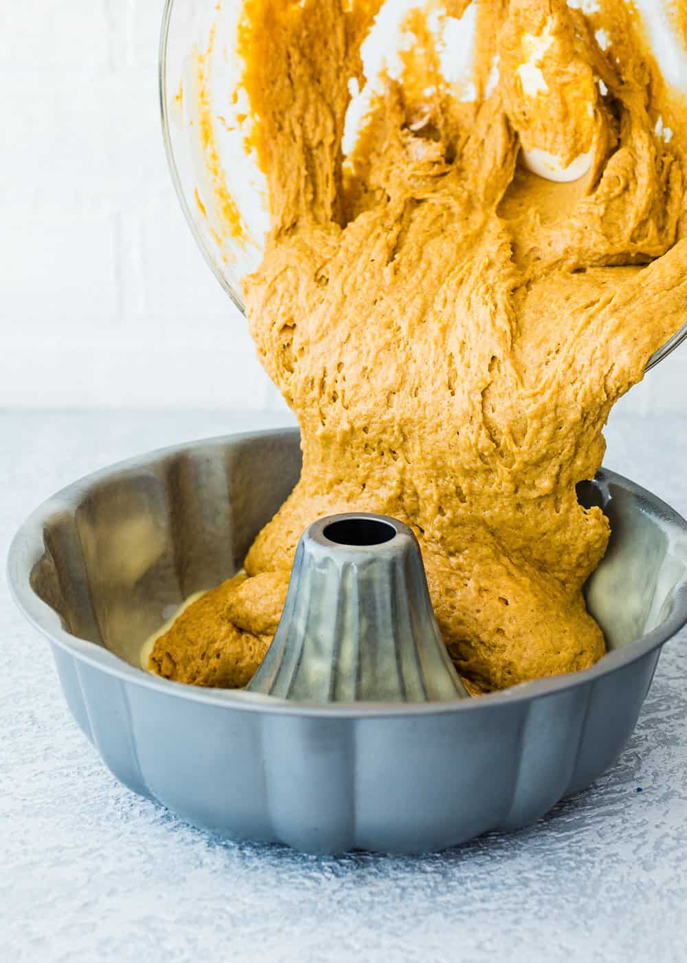 eggless pumpkin cake batter being poured into a bundt cake pan. 