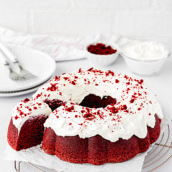 Eggless Red Velvet Bundt Cake with cream cheese frosting over a cooling rack