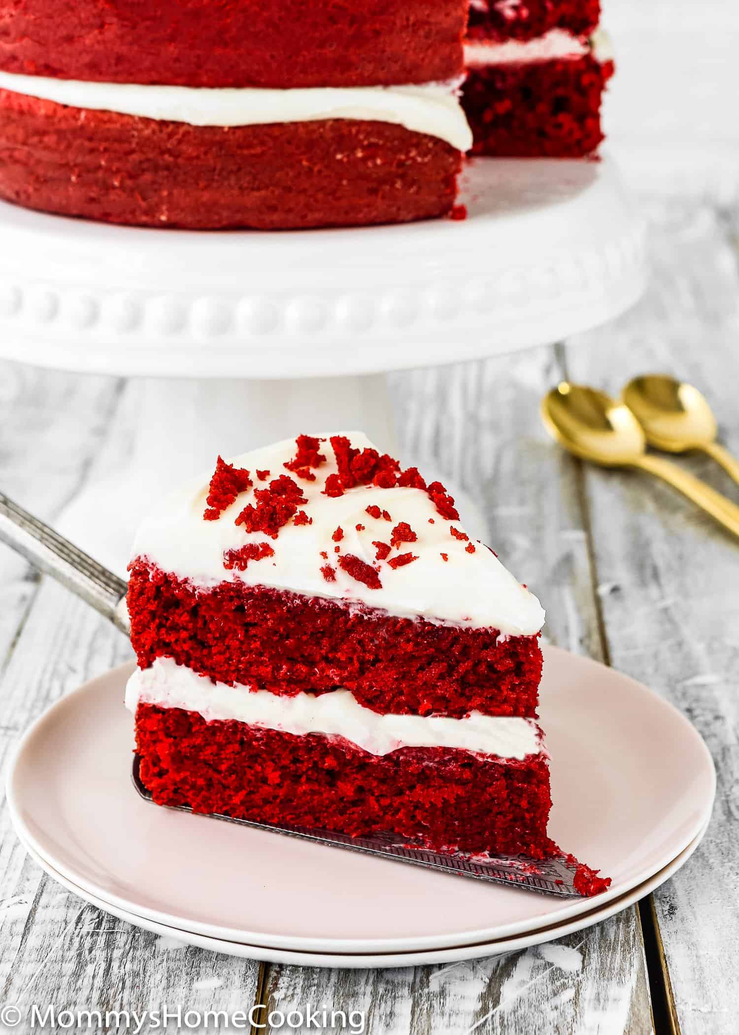 A slice of a two tiered eggless red velvet cake with cream cheese filling.