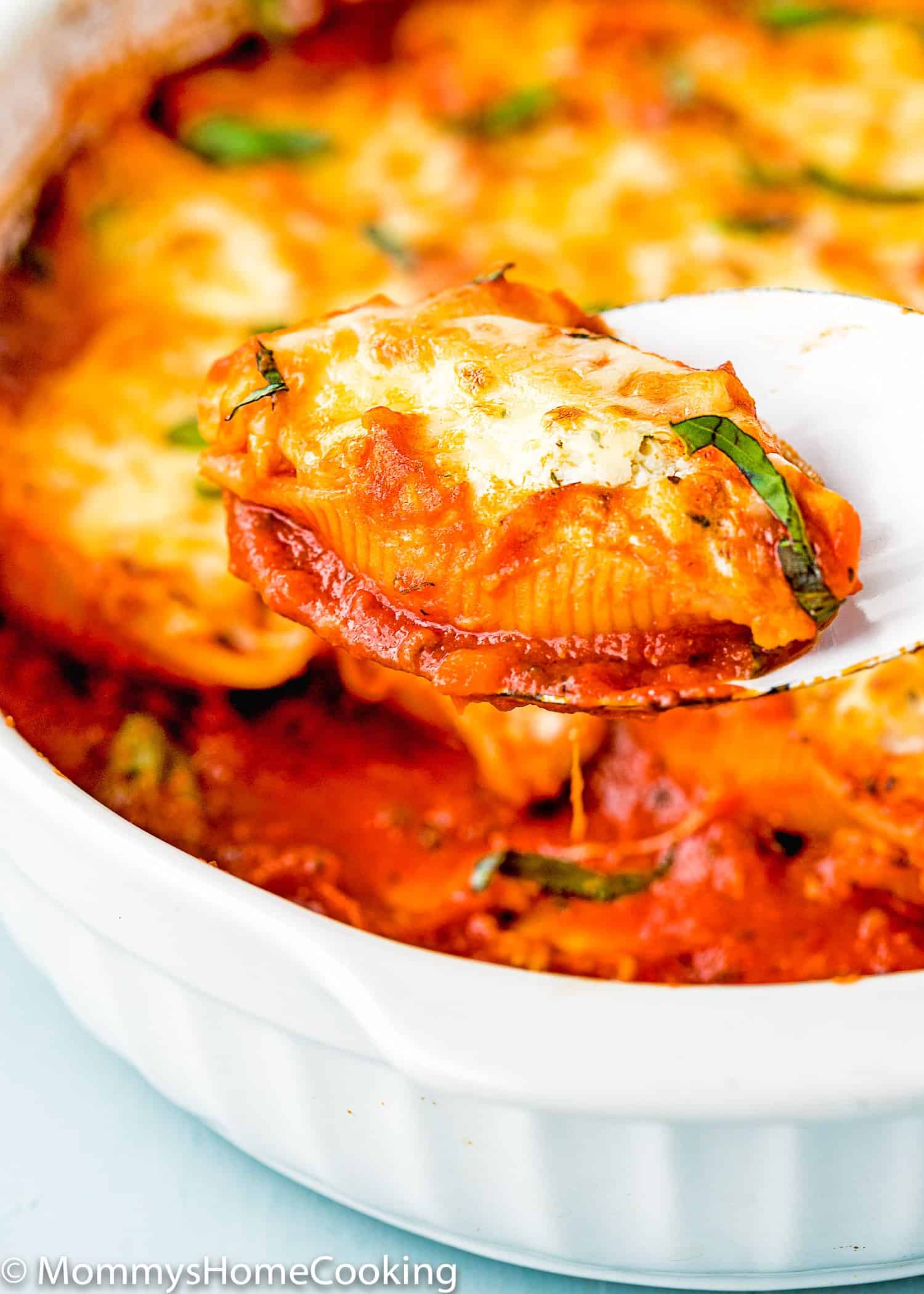 Eggless Ricotta Stuffed Shells in a white casserole in a serving spoon