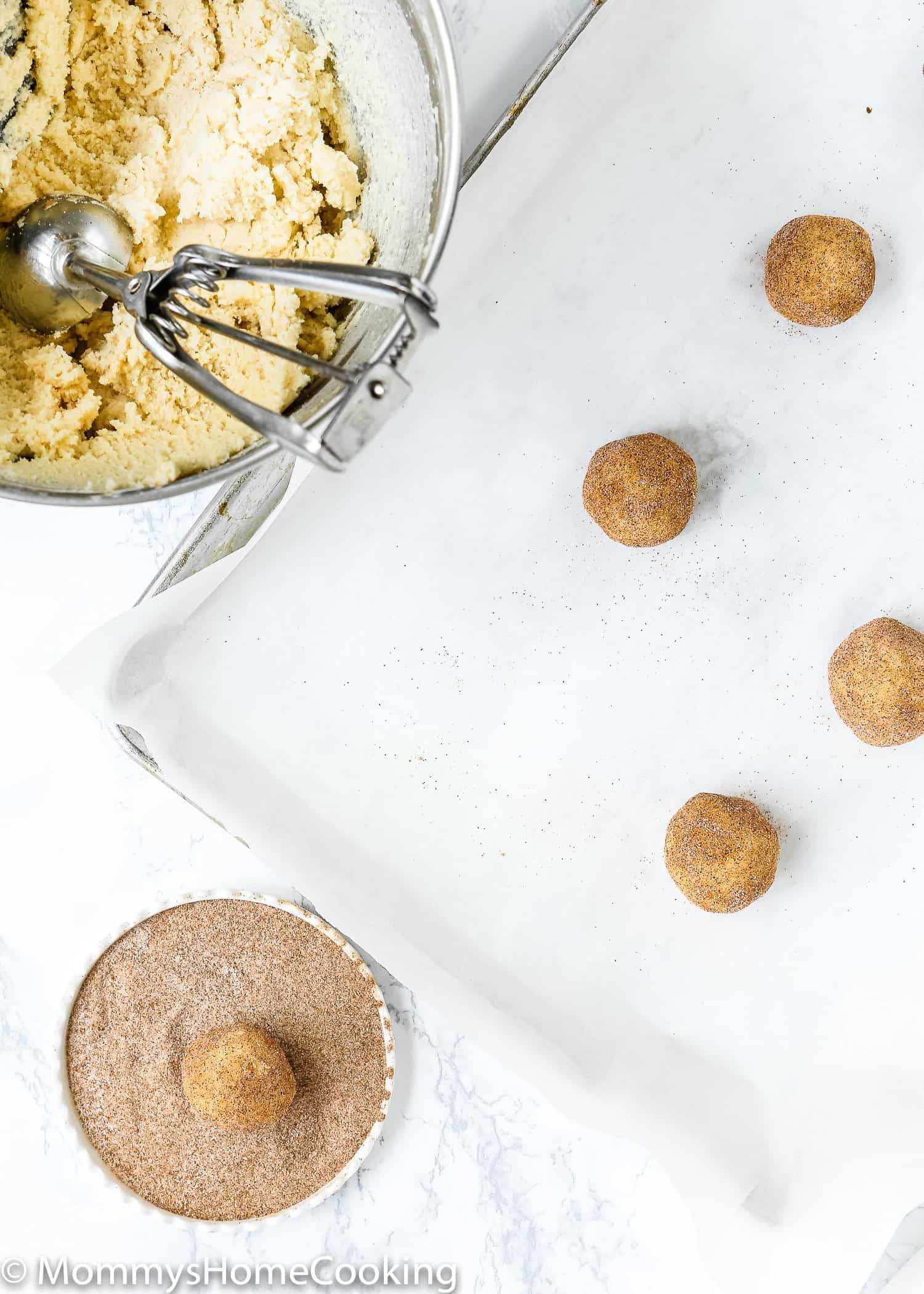 Eggless Snickerdoodle Cookie balls being rolled in cinnamon sugar.