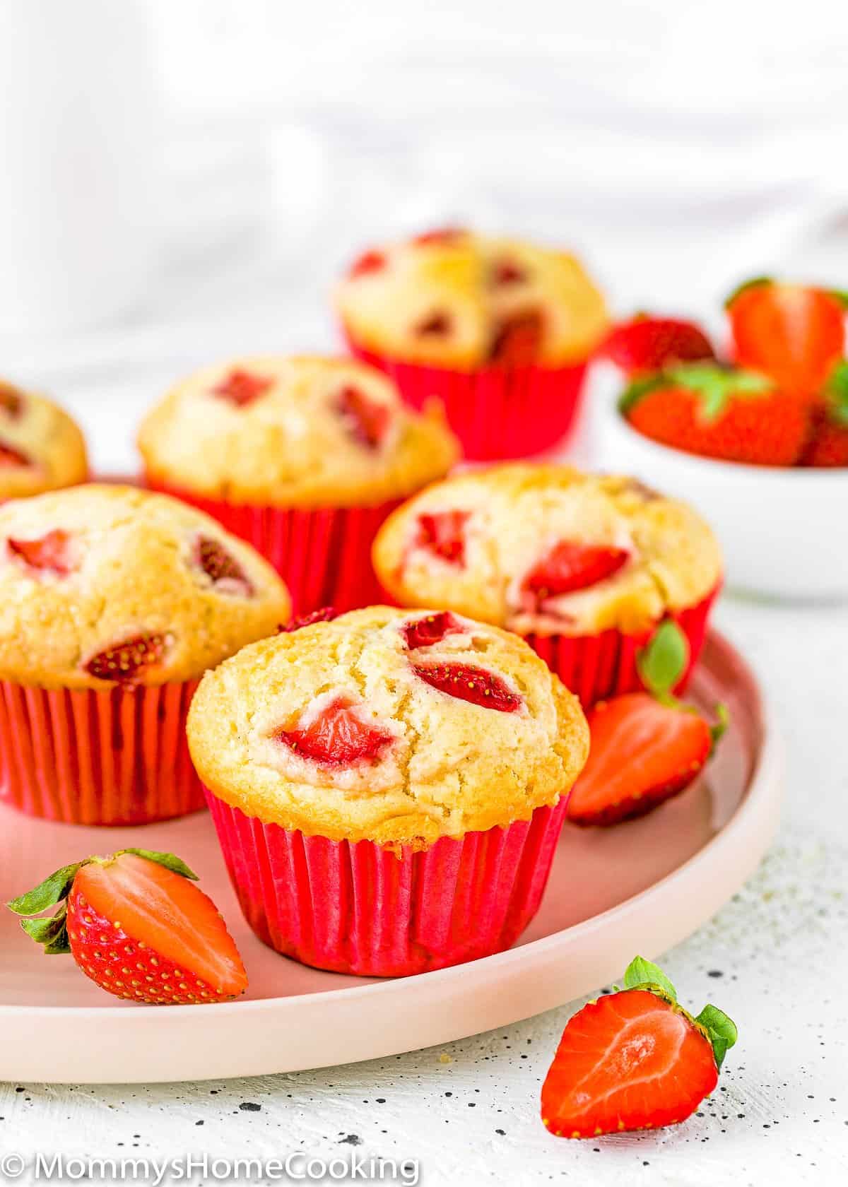 eggless strawberry muffins with fresh sliced strawberries on a plate.