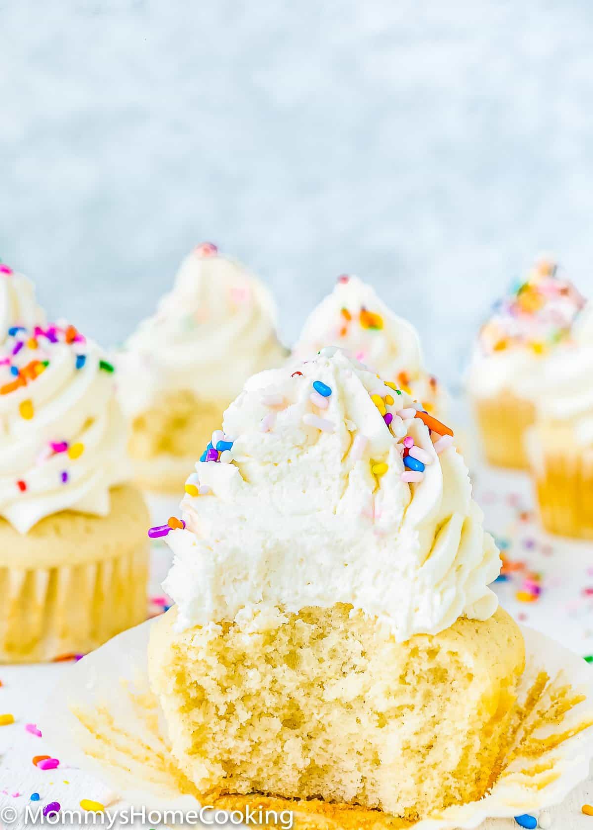 eggless vanilla cupcake bitten and showing fluffy inside texture. 