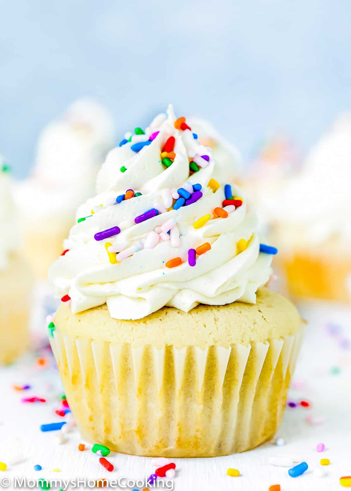 A fluffy and moist vanilla cupcake made without eggs with frosting and sprinkles on top.