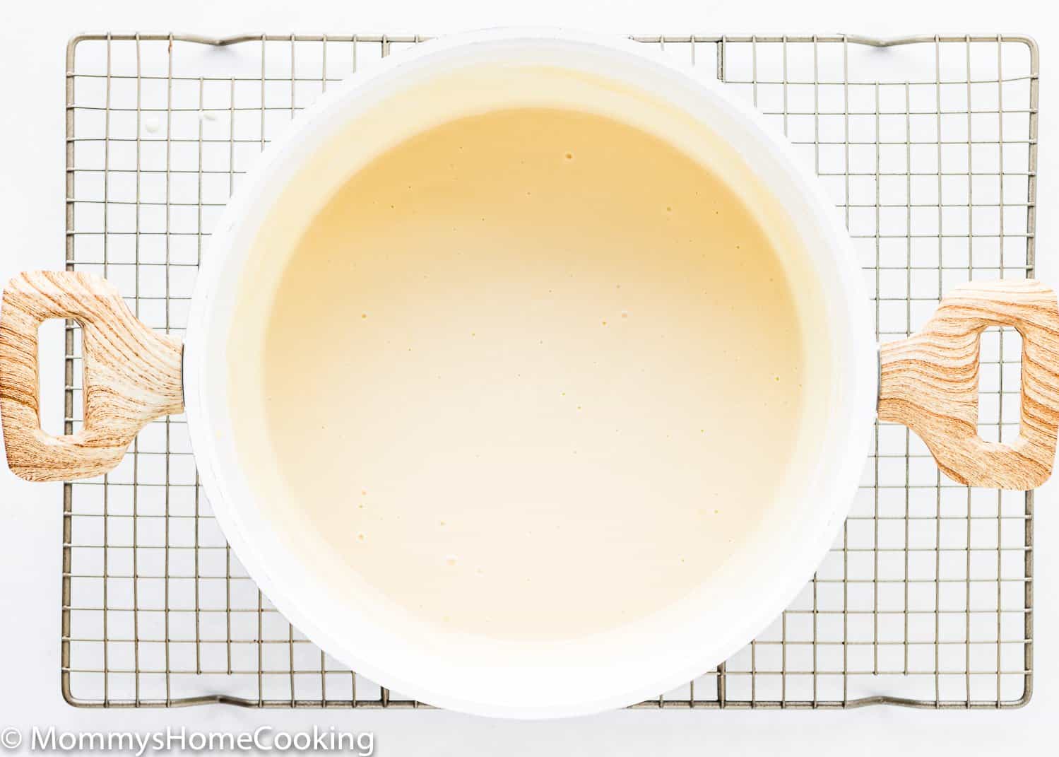 a pot with homemade egg-free vanilla pudding over a cooling rack.