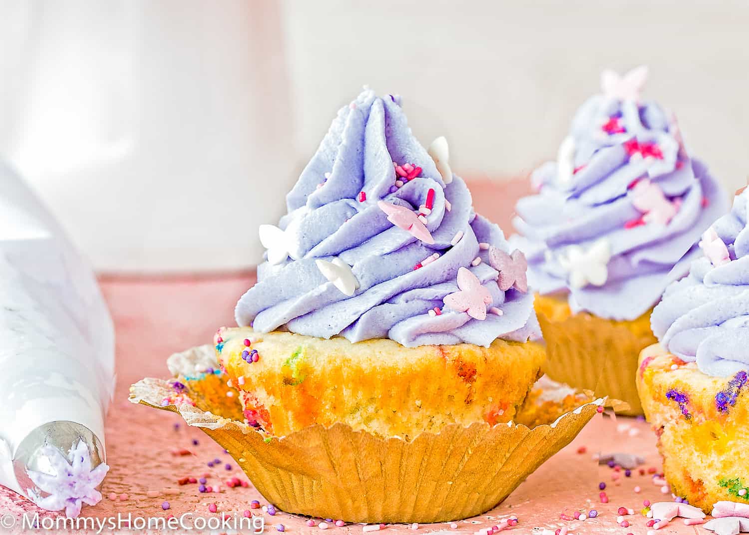 a Eggless Funfetti Cupcakes with purple buttercream and sprinkles.