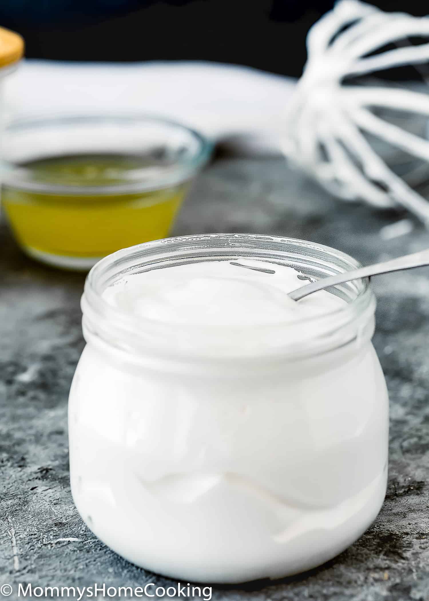 Homemade Eggless Marshmallow Fluff in a glass jar with a spoon in it.