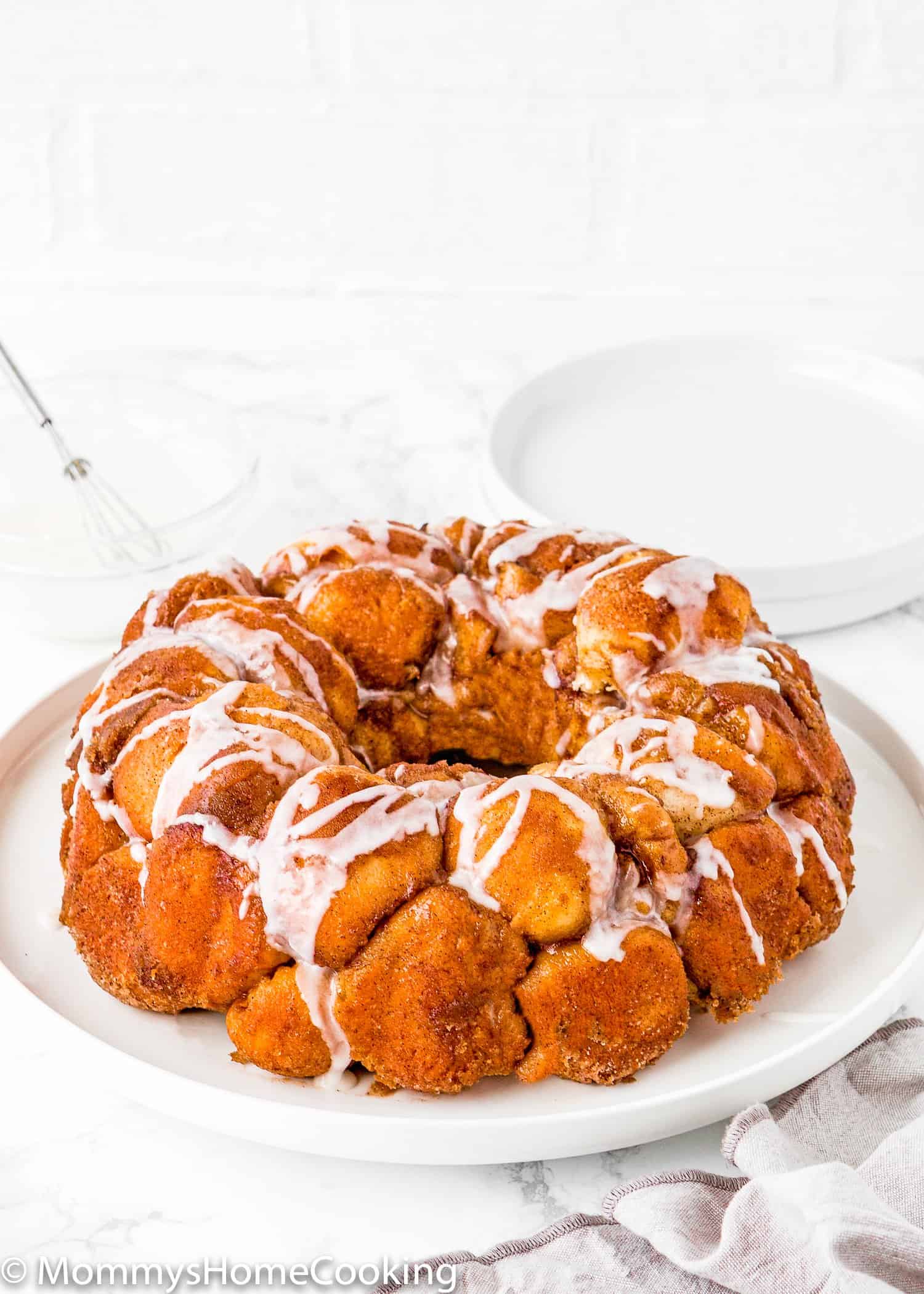 Homemade Eggless Monkey Bread on a plate drizzled with sugar glaze.