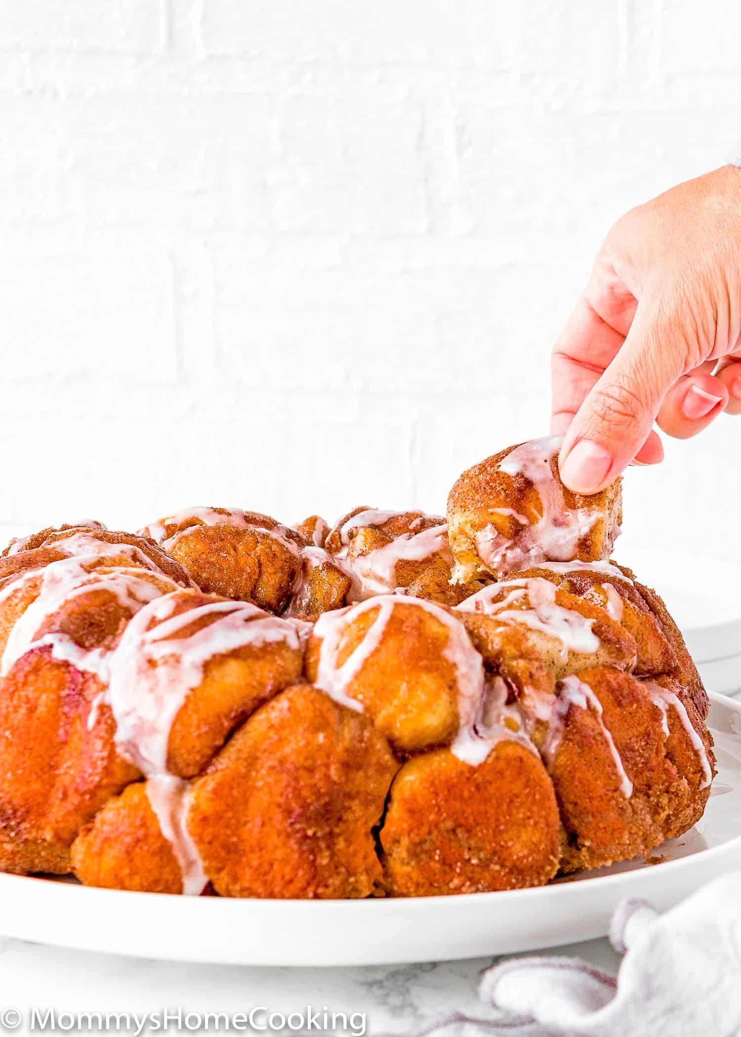 a hand tanking a piece of Homemade Eggless Monkey Bread.