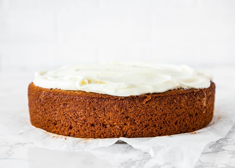 egg-free banana cake with cream cheese frosting on top over a marble surface. 