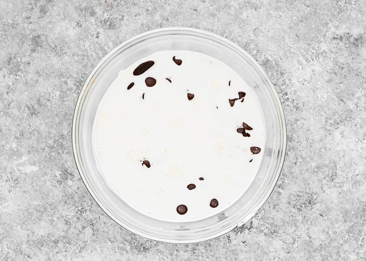 a bowl with dark chocolate chips and hot heavy cream 