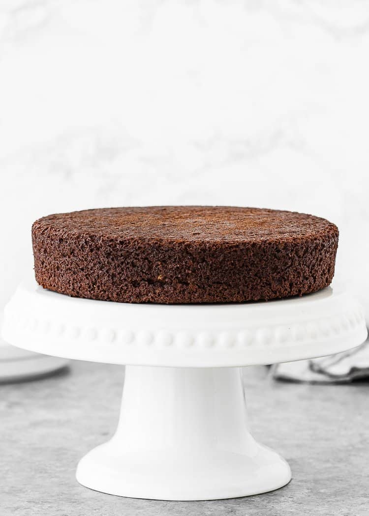 an egg-free chocolate cake layer over a cake stand. 