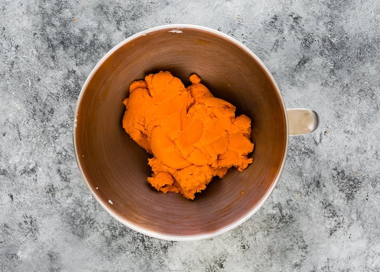 Egg-Free Orange Halloween Cookies dough in a stand mixer bowl. 