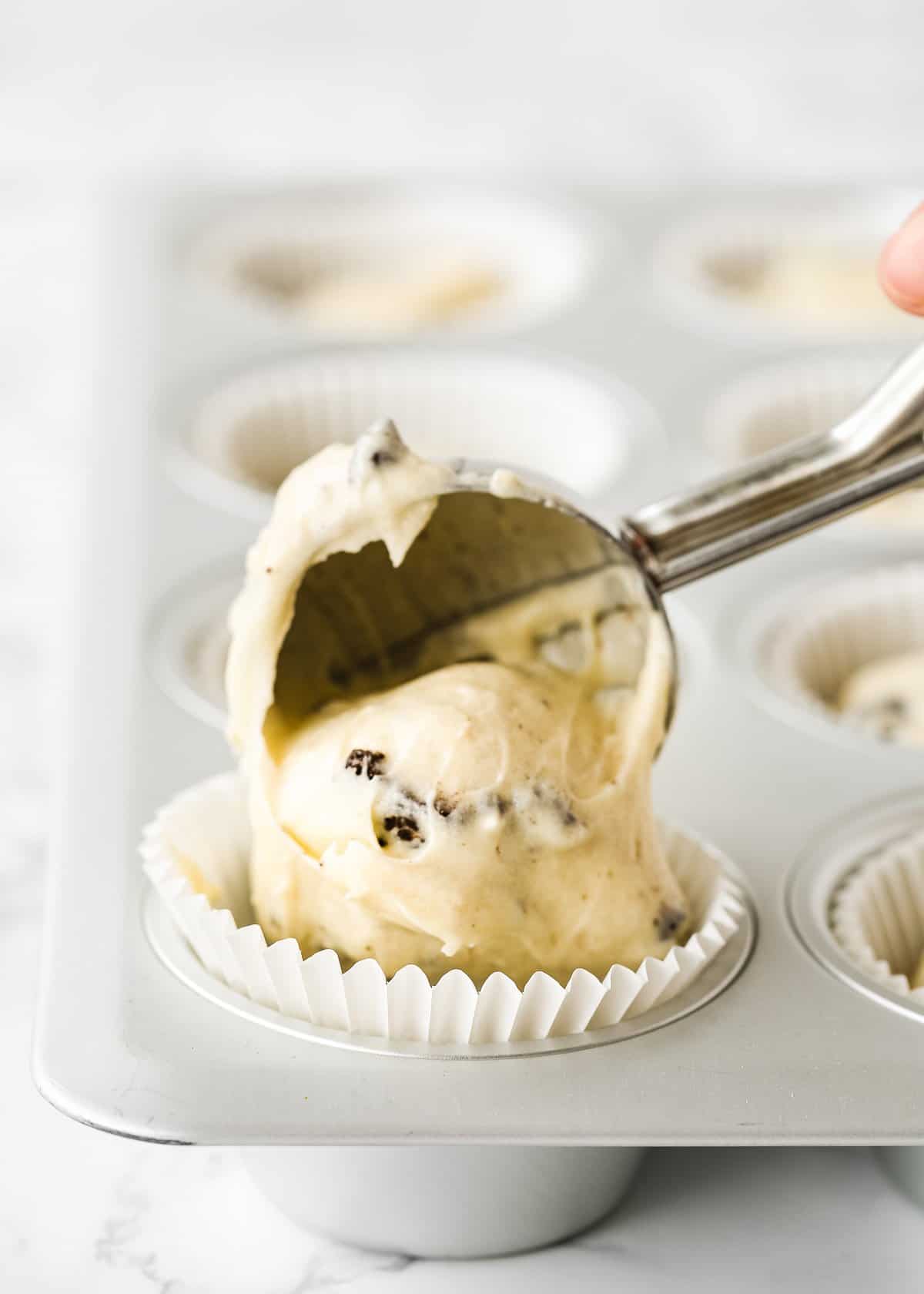 an ice cream scoop, scooping eggless oreo cupcakes batter into a cupcake liner. 