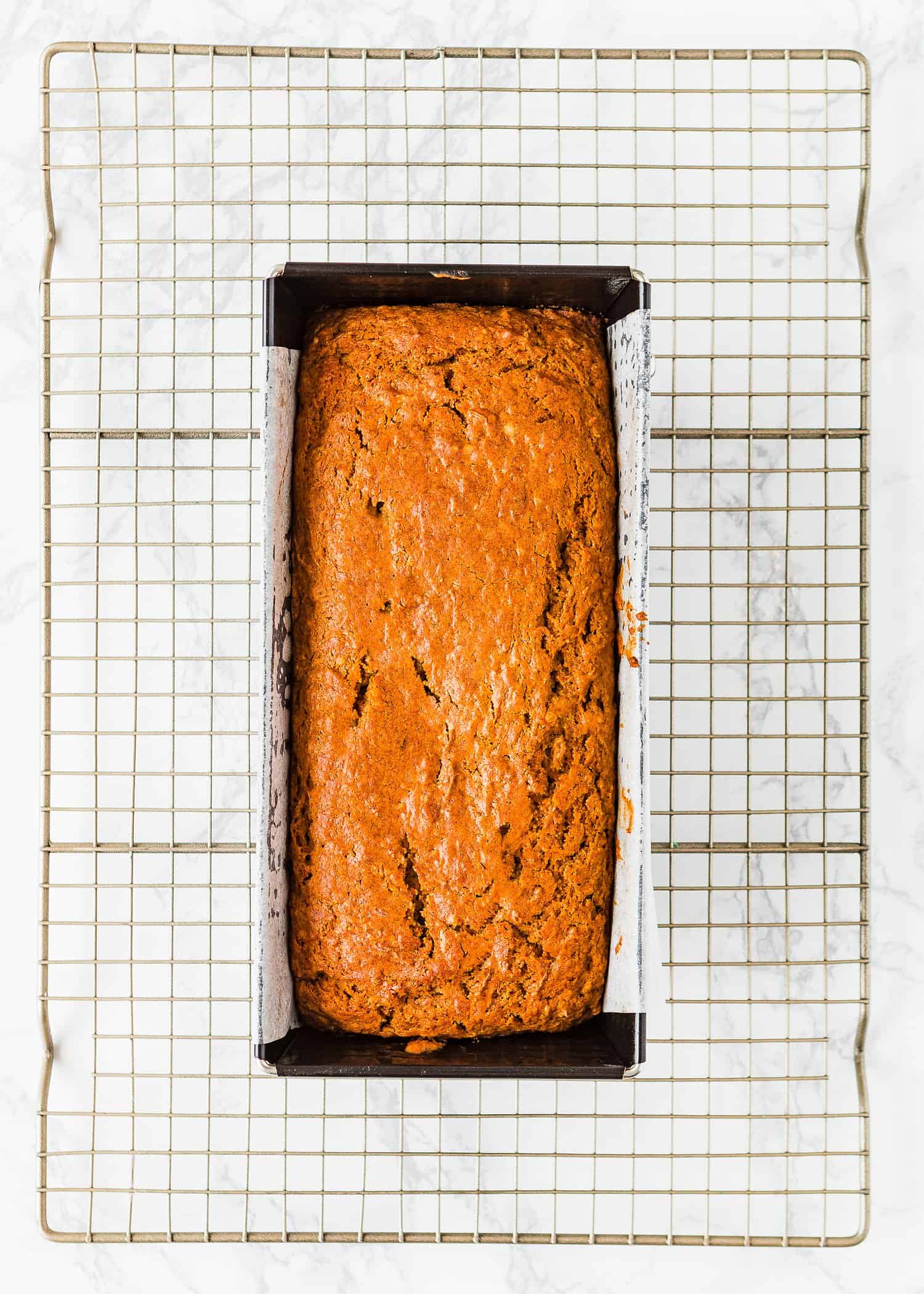 Eggless Carrot Cake in a Loaf pan over a cooling rack. 