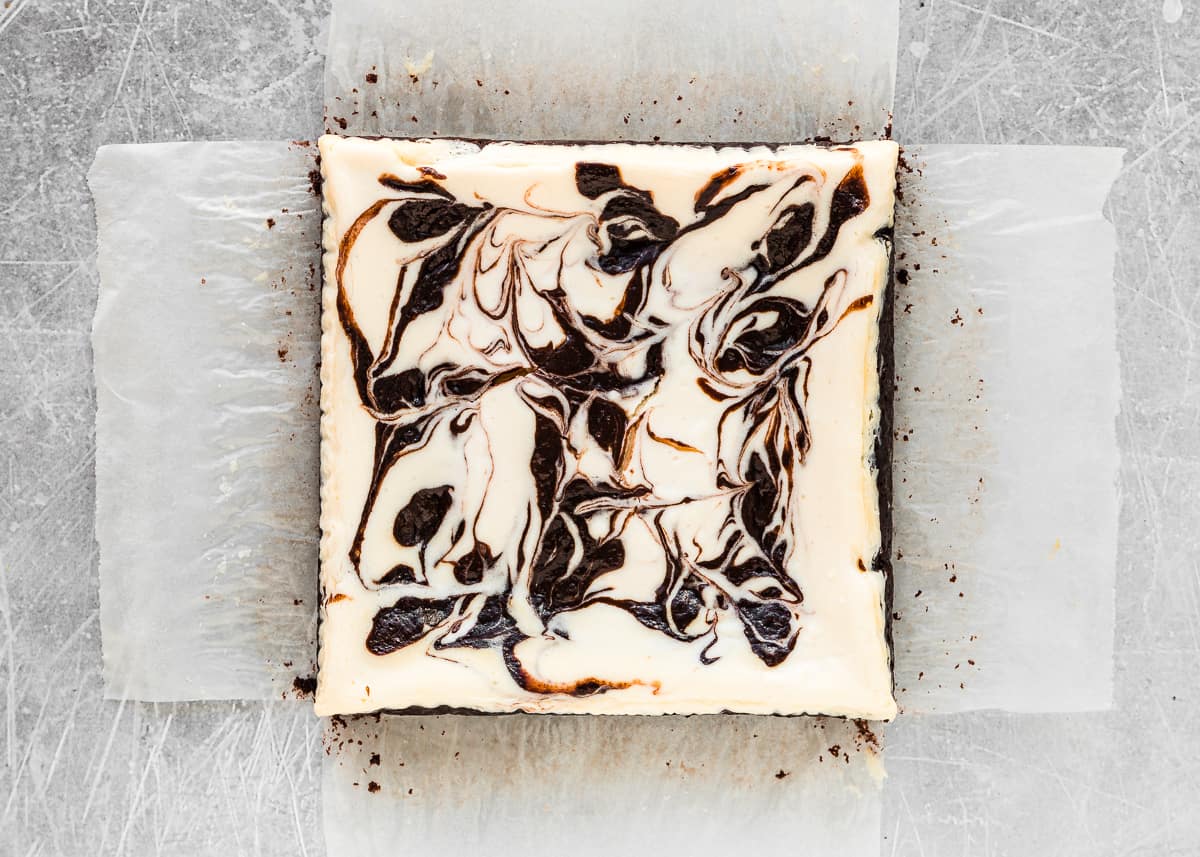 baked eggless cheesecake brownies over parchment paper.