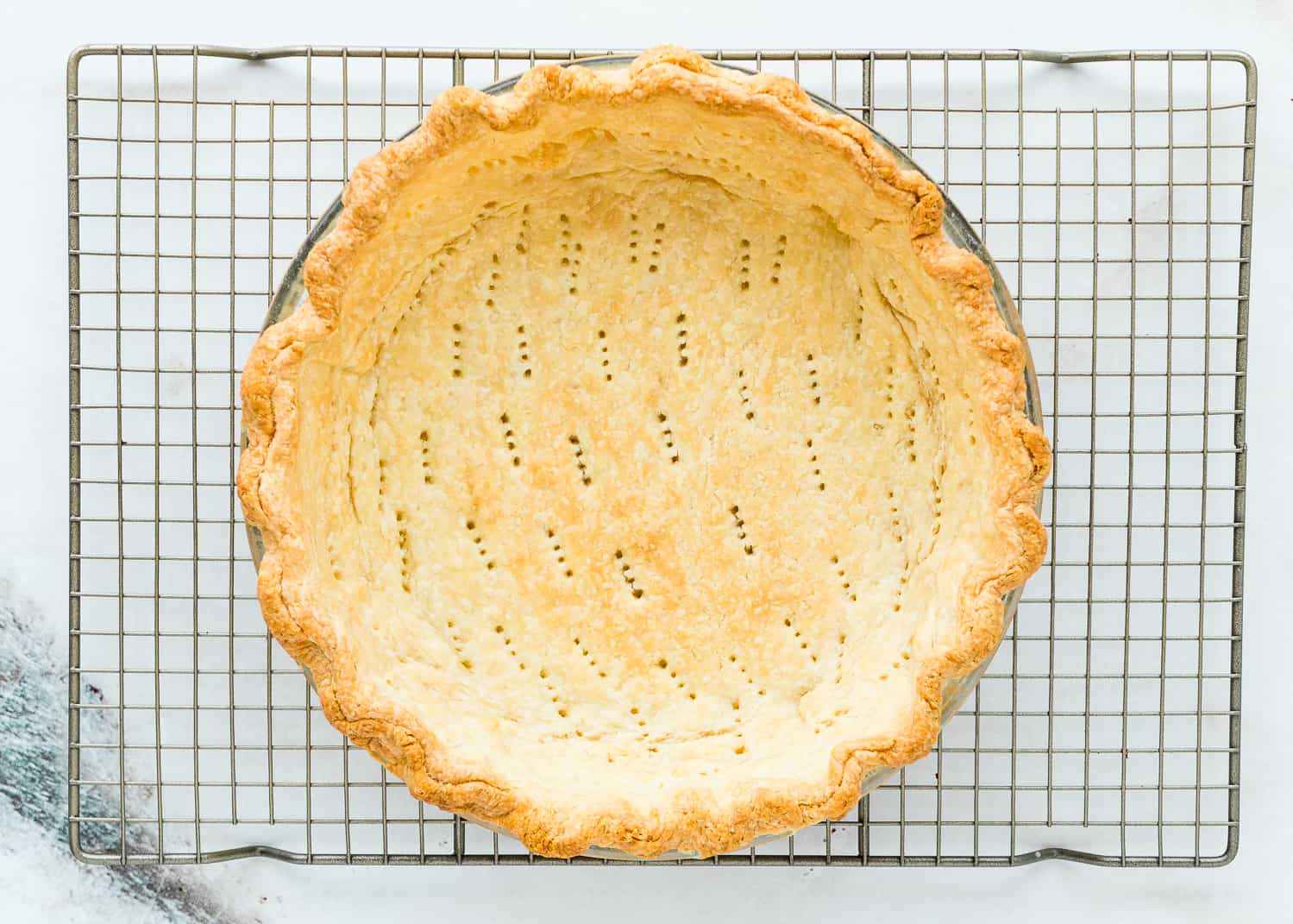 blind baked pie crust in a pie dish over a cooling rack. 