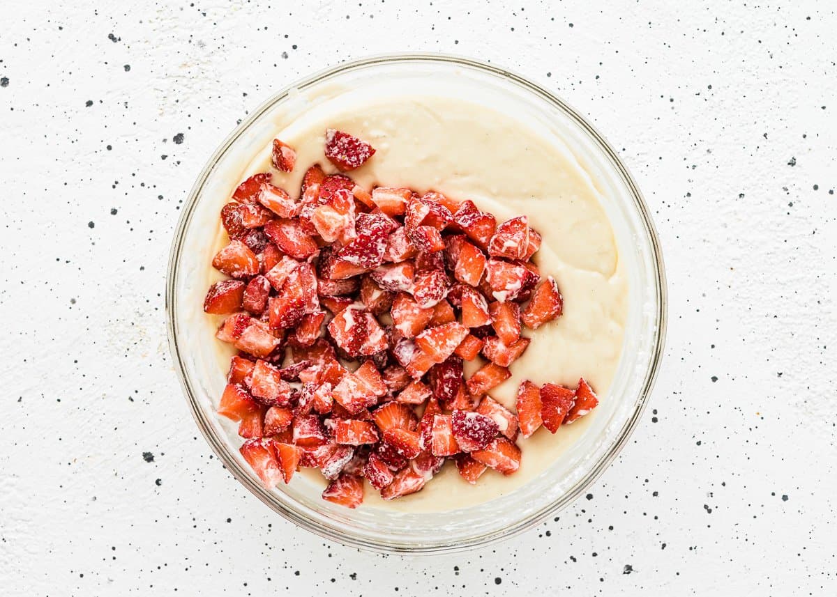 egg-free muffin batter in a bowl with fresh chopped strawberries on top. 