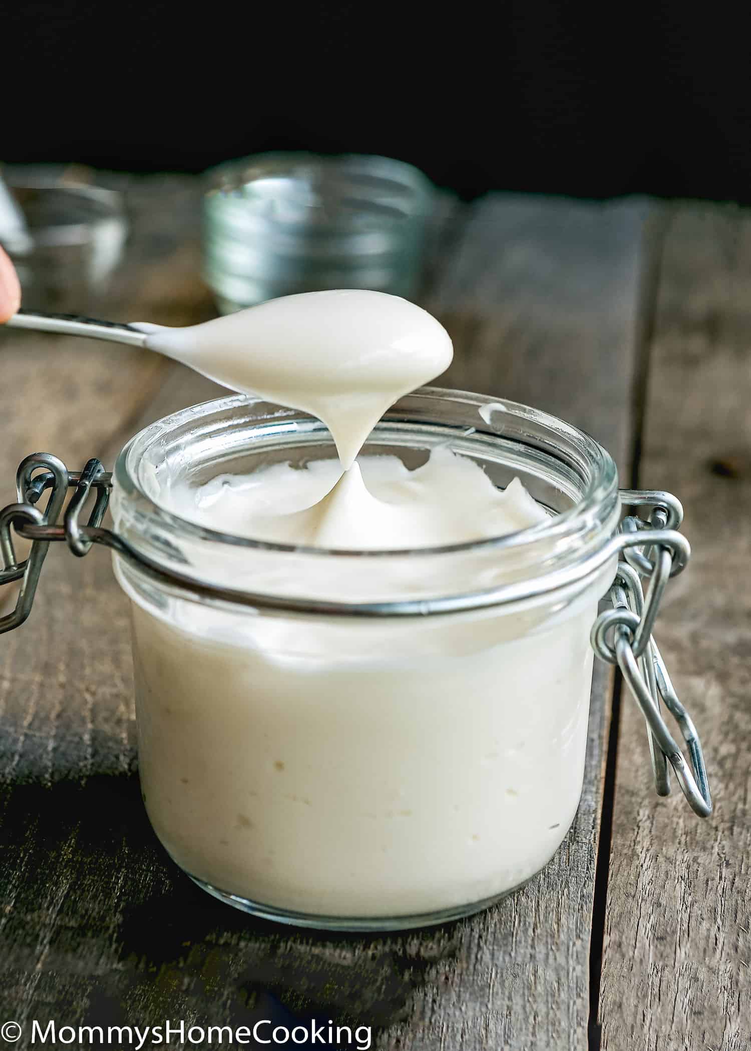 a spoon spooning out some egg-free mayonnaise from a glass jar.