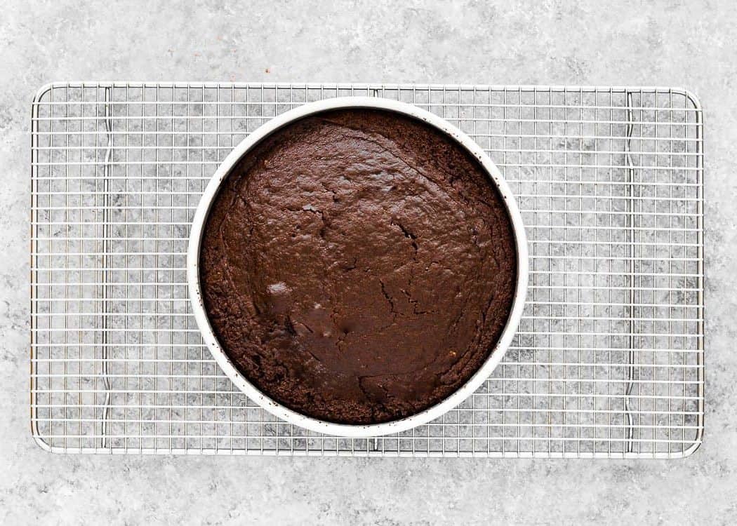 Eggless Chocolate Cake in cake pan over a cooling rack. 