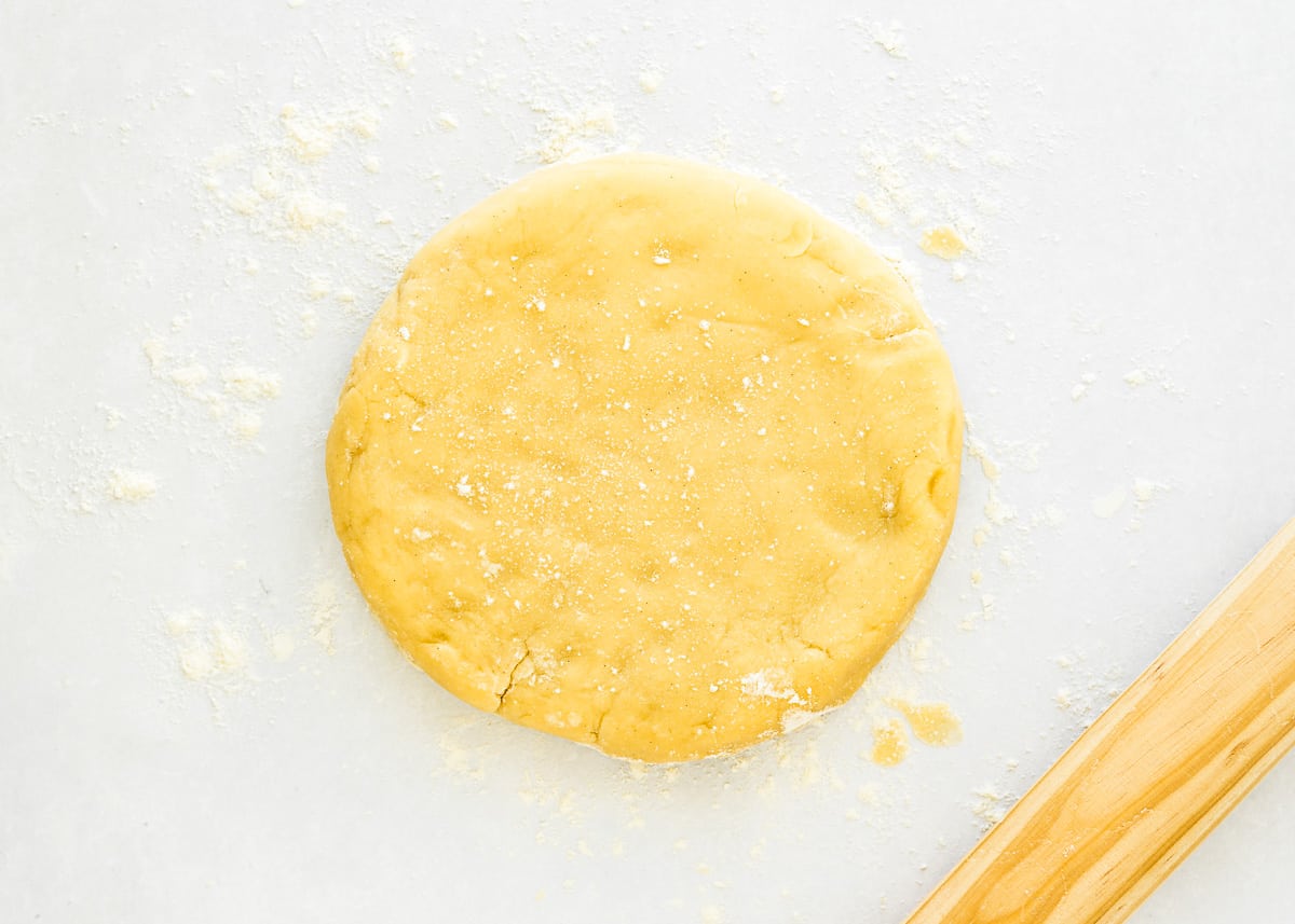 eggless tart dough on a floured surface with a rolling pin on the side.