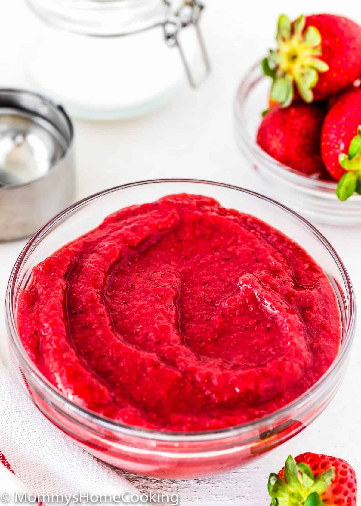 strawberry puree in a bowl with fresh strawberries in the side.