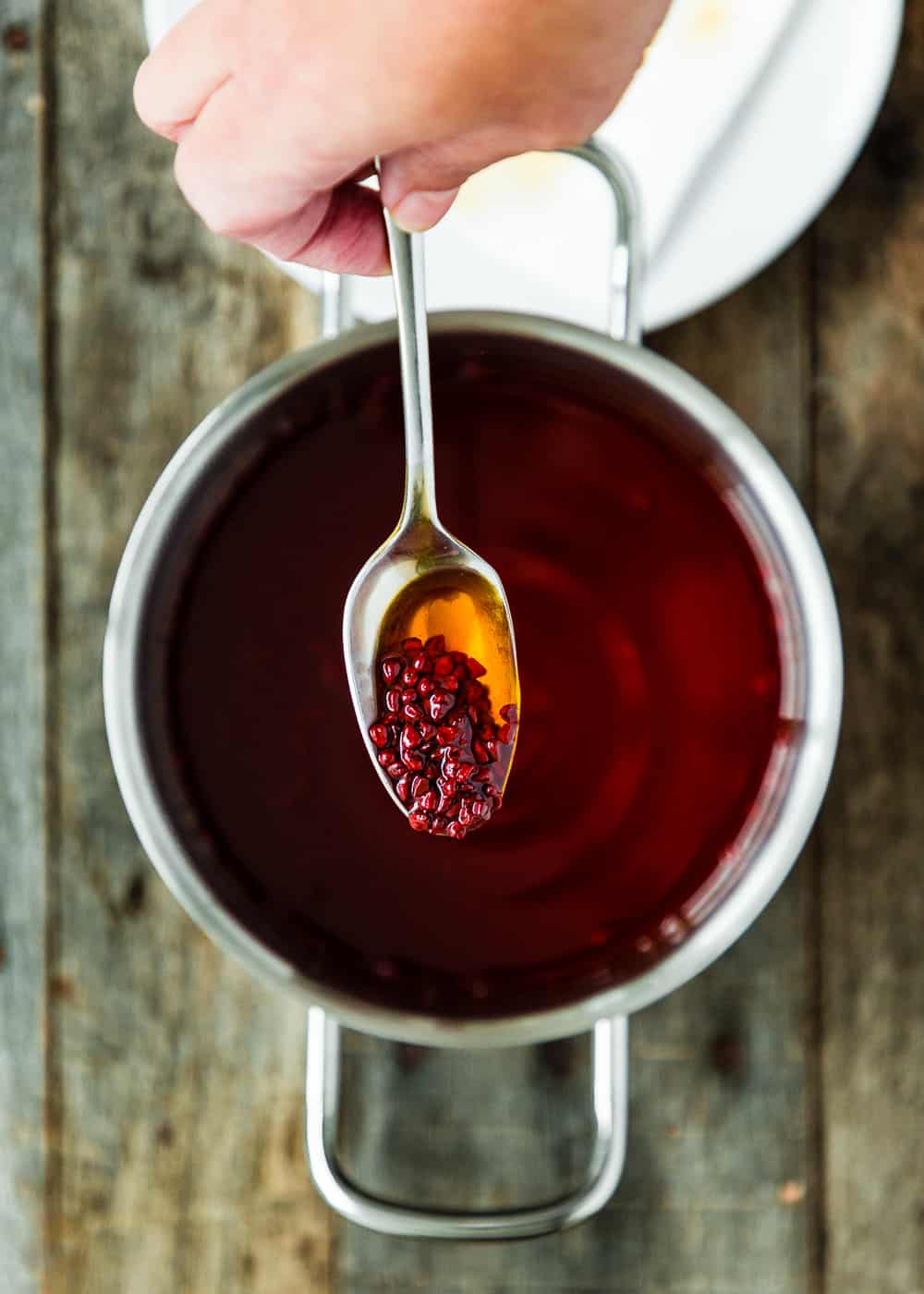 a hand holding a spoon with Venezuelan Onoto achiote oil for Hallacas