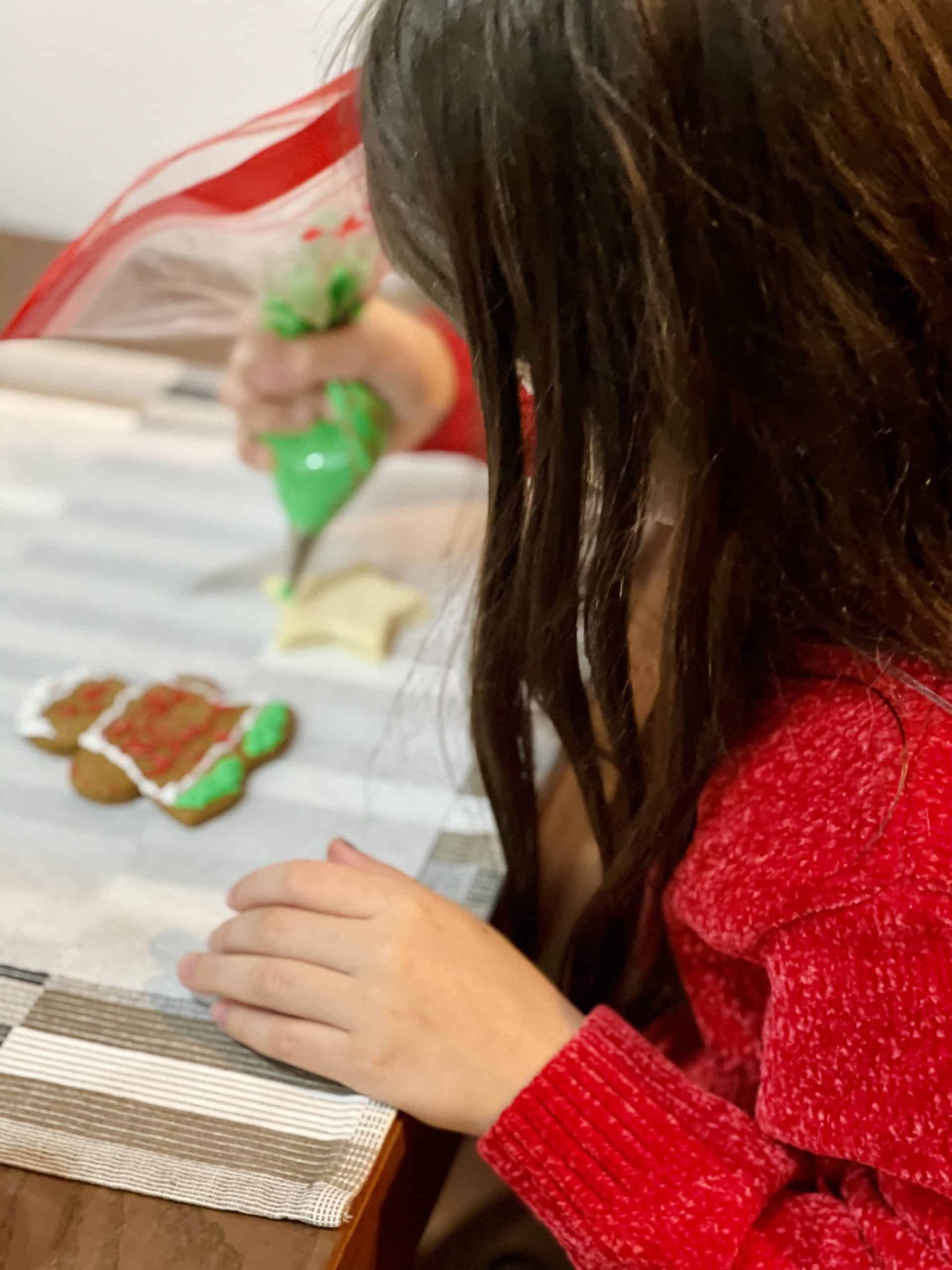 a little girl decorating egg-free gingerbread cookie. 