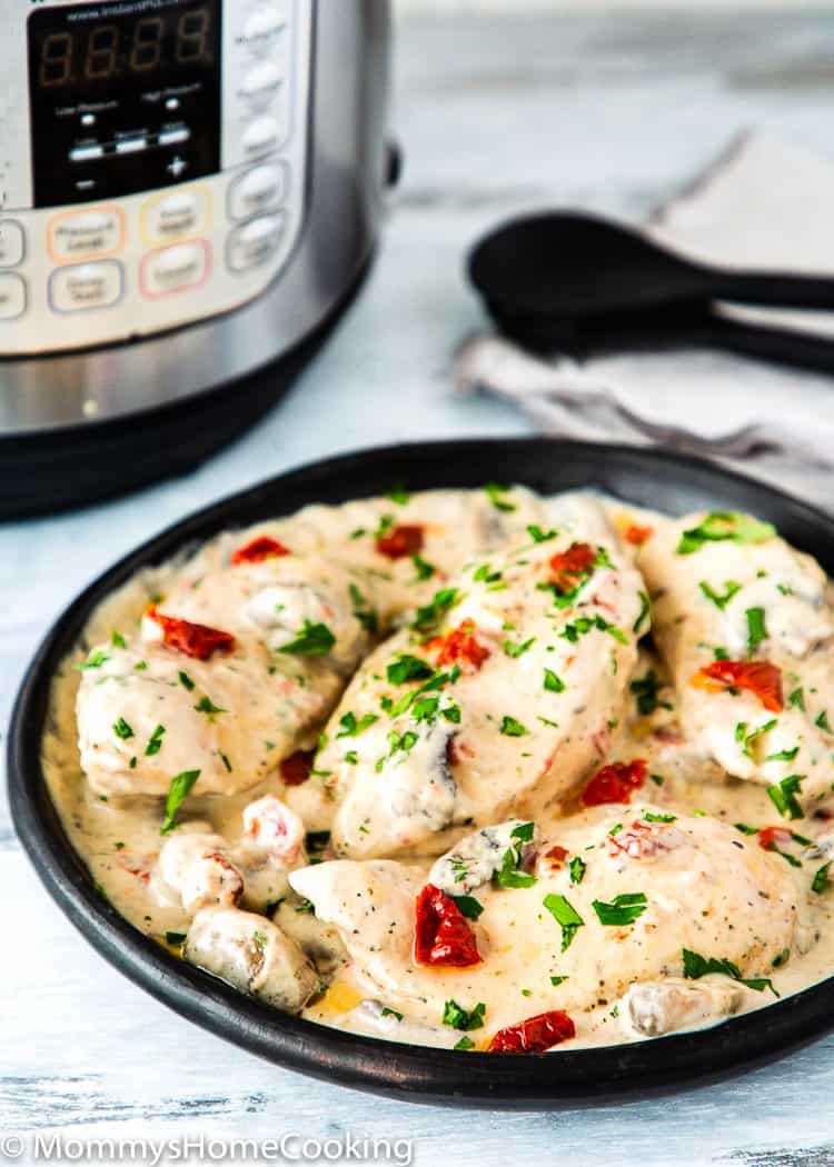 Instant Por Creamy Chicken and Mushrooms in a black plate with a pressure cooker in the background 