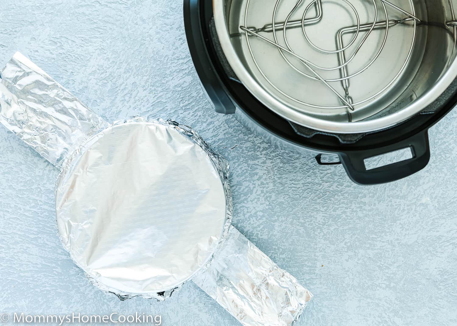 an instant pot with a springform pan covered with foil and over a foil sling.