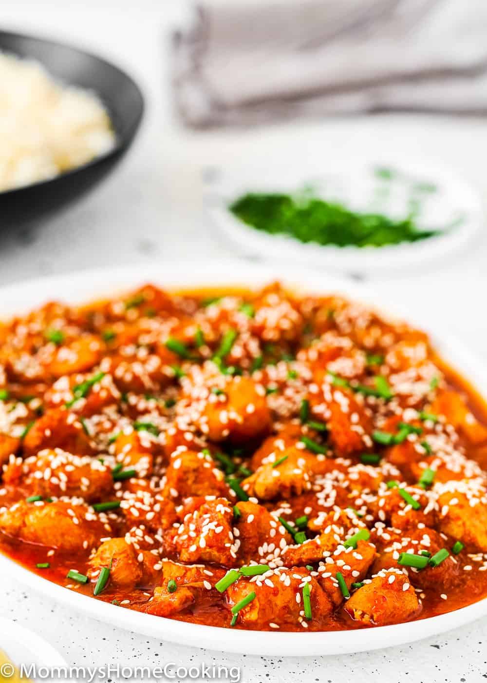 Instant Pot Korean Kimchi Chicken in a white plate sprinkle with sesame seed and chives