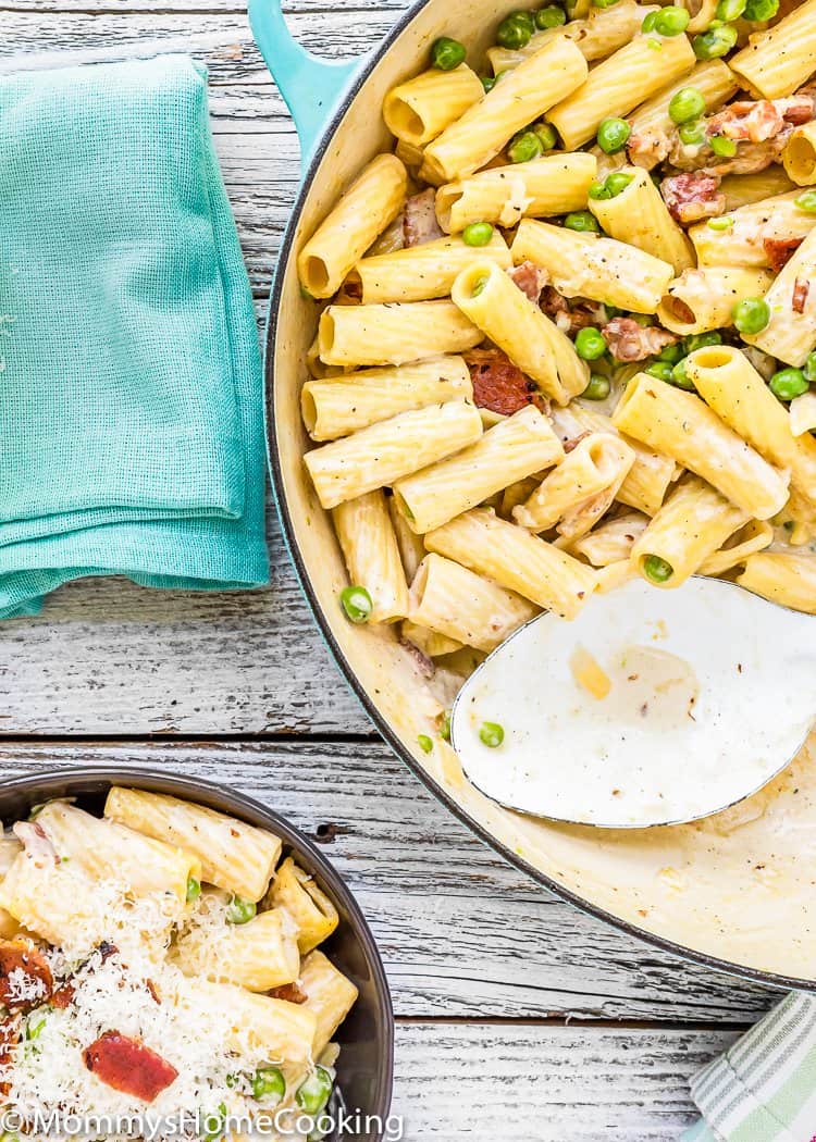 Creamy Alfredo Pasta with Bacon and Peas in a pot with a serving spoon