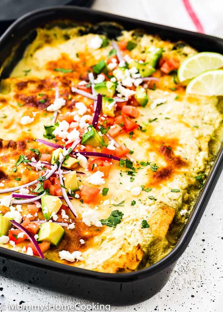 Easy Enchiladas Suizas in a baking dish with onions, avocado and tomatoes