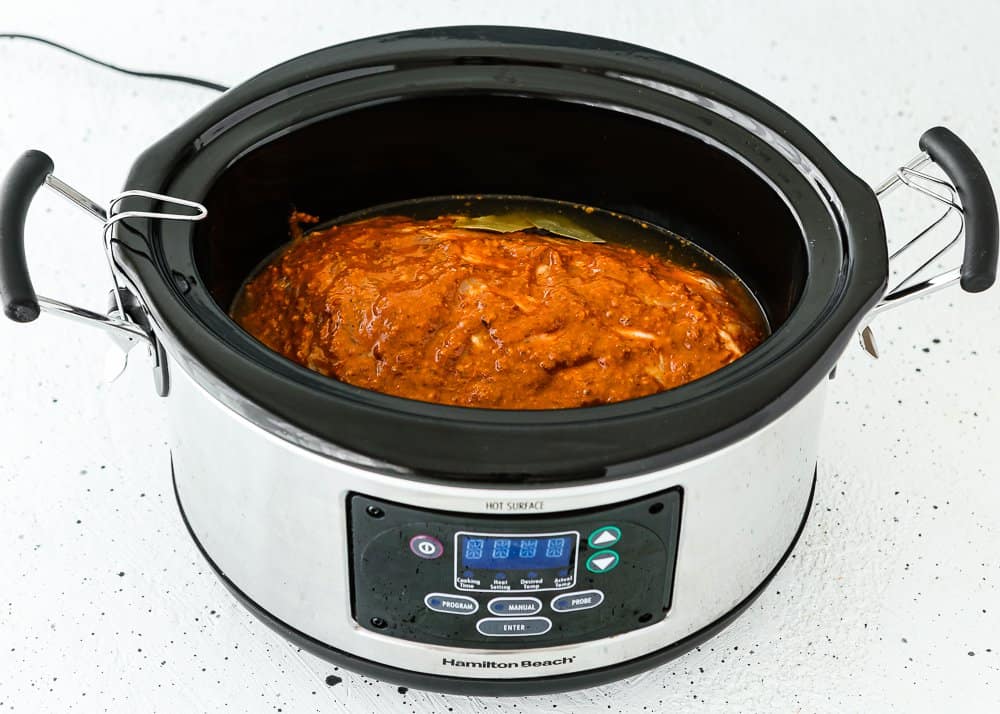 raw pork shoulder with chipotle sauce in a slow cooker. 
