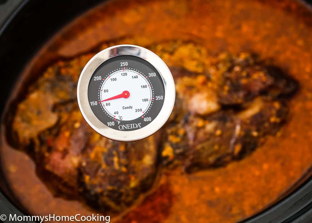 A meat thermometer stuck in pork showing 150ºF.