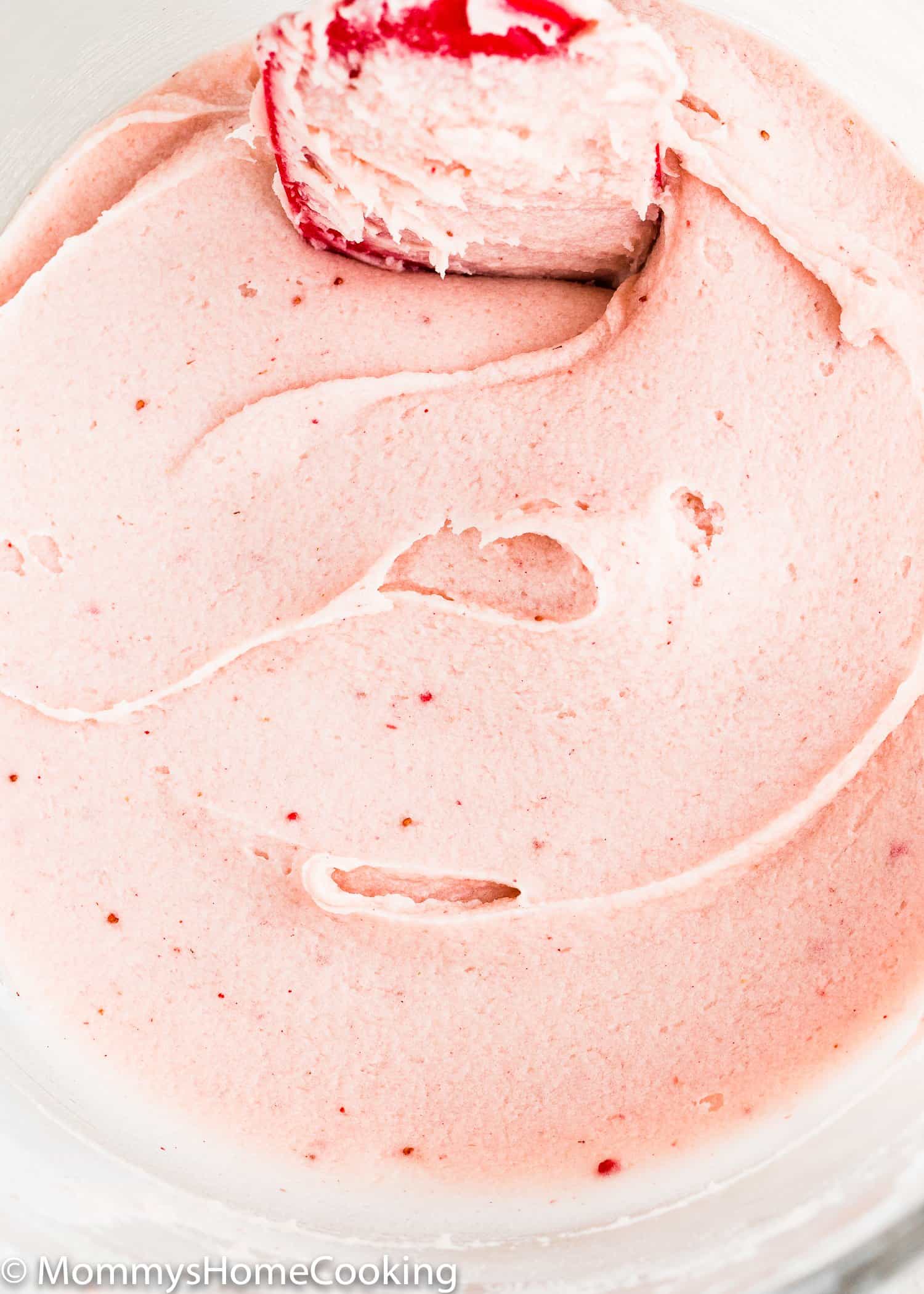 Strawberry buttercream in a bowl with a red spatula. 