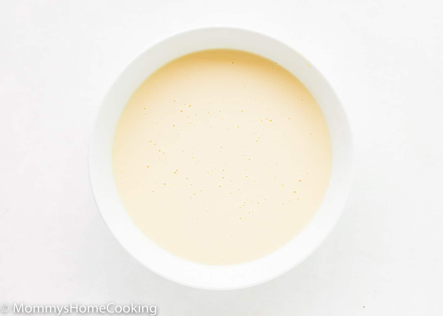 Eggless vanilla pudding in a white bowl.