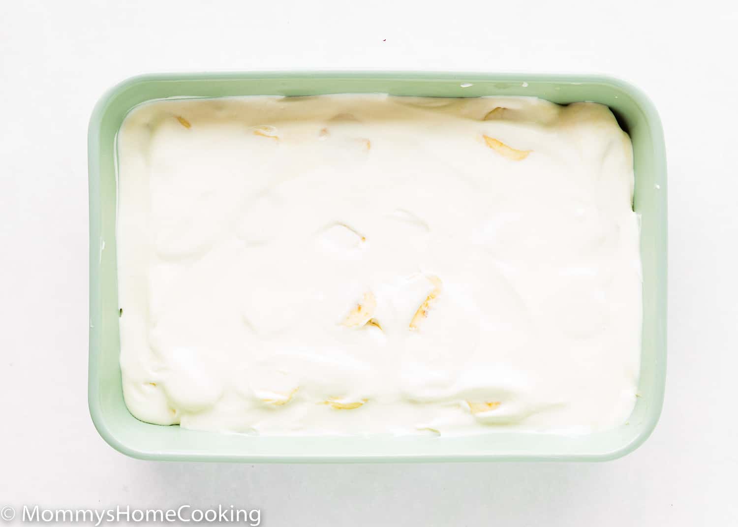 A layer of banana pudding in a rectangular green dish.